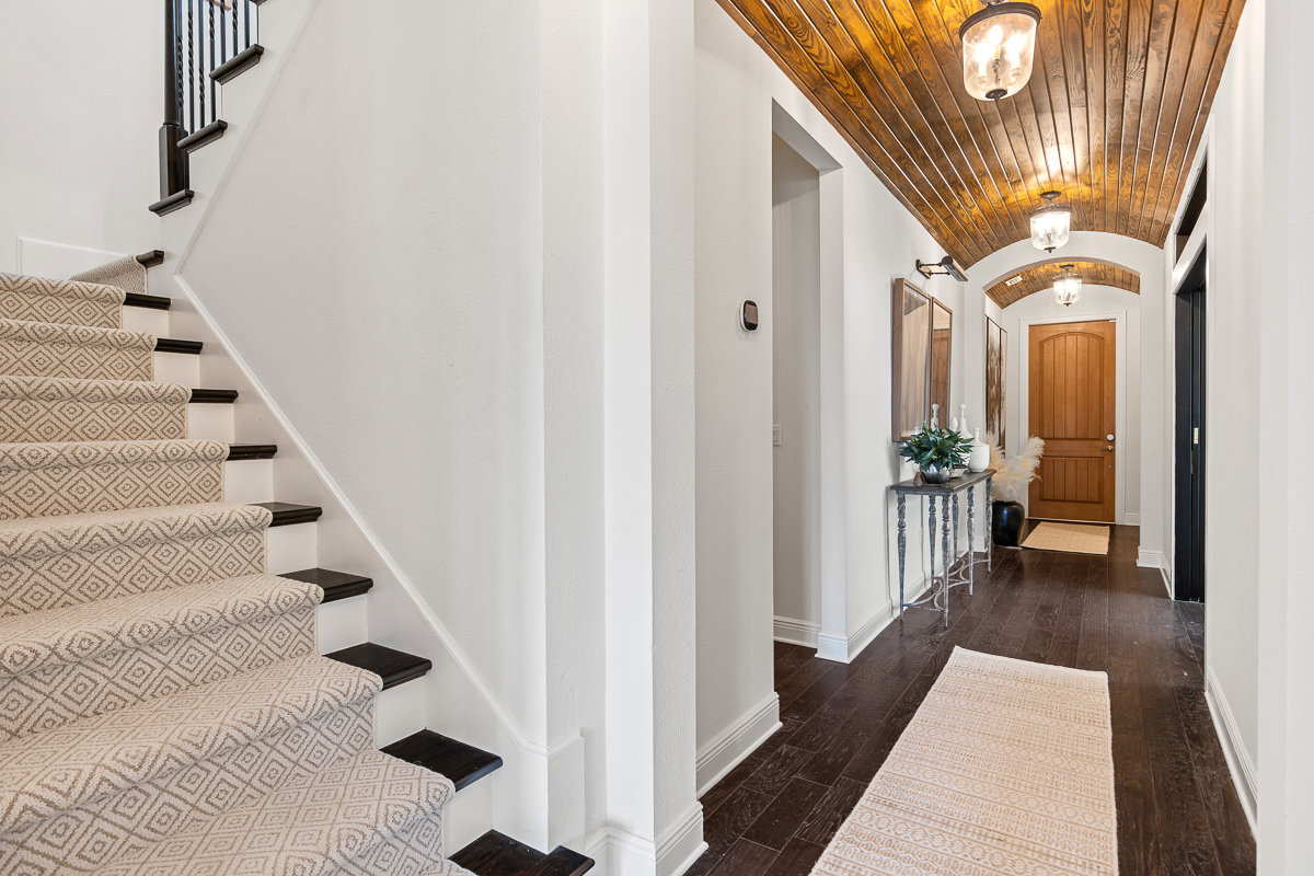 white entryway with brown wood accents and stairs